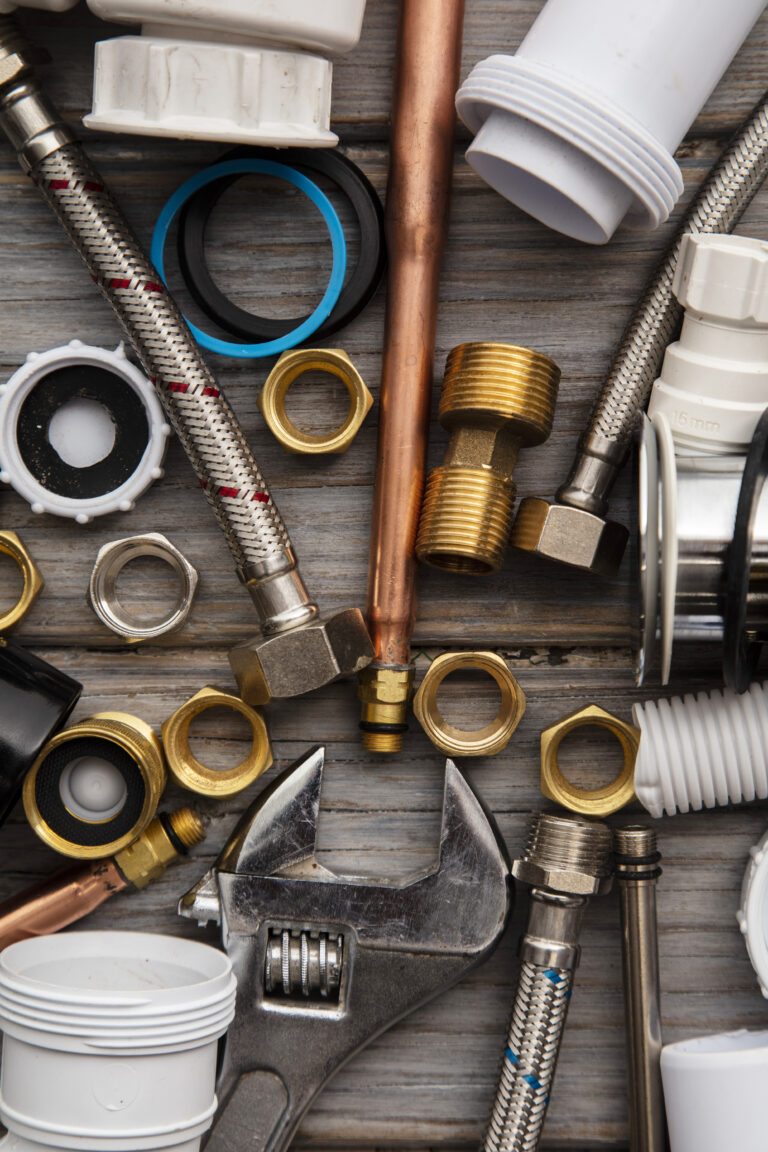 Plumbing tools, pipe and fixings on a rustic wooden background